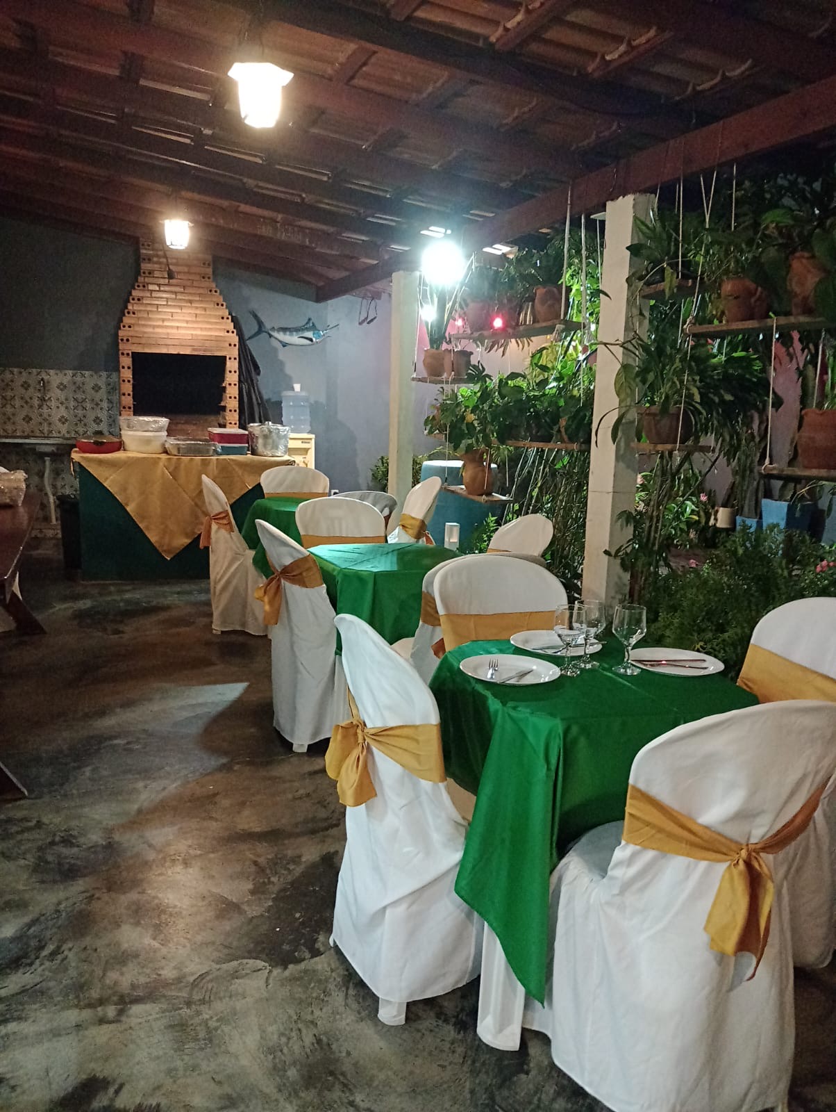 Varanda coberta com churrasqueira e mesas na Casa Bella Eventos
